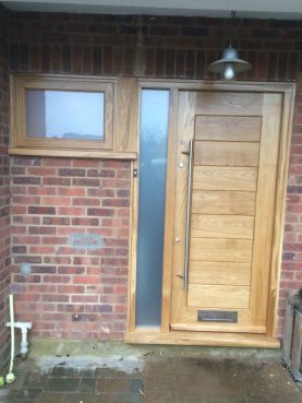 Solid contemporary oak door with frosted glazed side panel and long entrance handle. Bespoke joinery