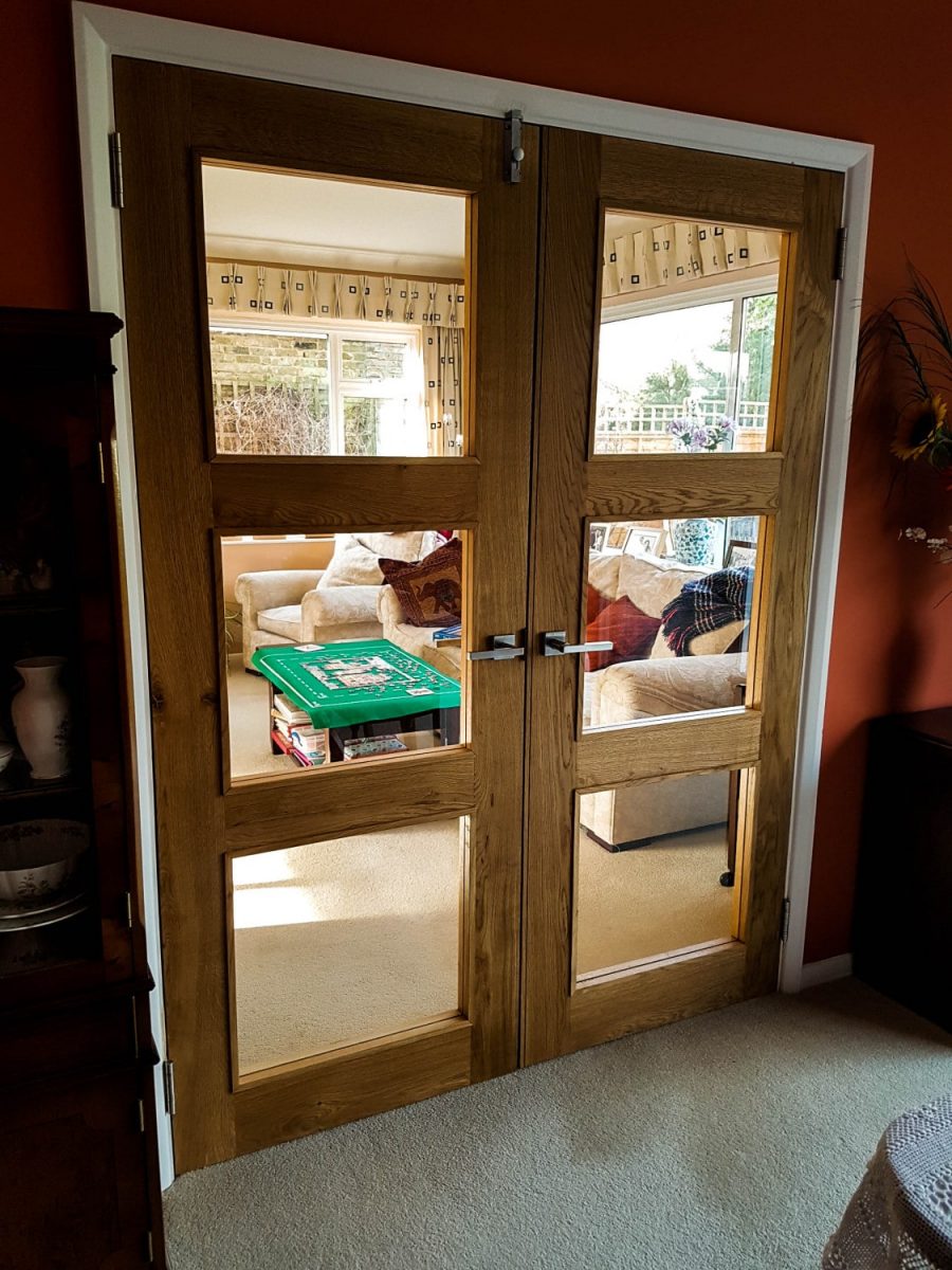 Room dividing glazed oak doors with square glass panes and brushed silver handles