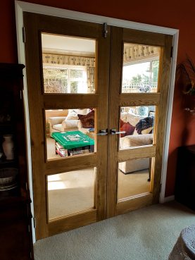 Room dividing glazed oak doors with square glass panes and brushed silver handles
