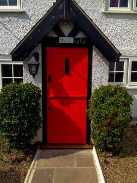 Bright red bespoke stable door in cottage style with antique black door furniture. Joinery herts
